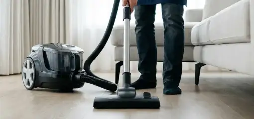 Professional house cleaner vacuuming a living room floor with a canister vacuum cleaner, Houston, TX.